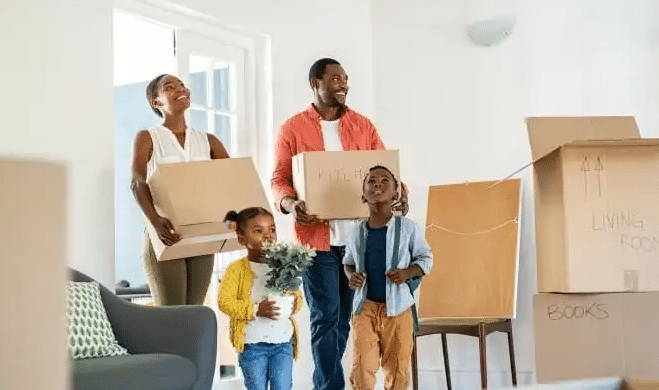 Happy family standing in front of their new home, benefiting from a strong credit score and low mortgage interest rate.